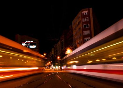 Twin trains speed past each other at night in a vibrant urban setting, creating a dynamic city atmosphere.
